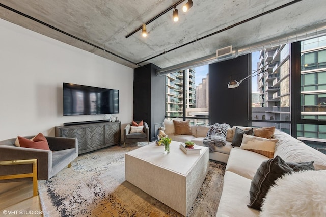 living area featuring rail lighting, floor to ceiling windows, visible vents, and wood finished floors