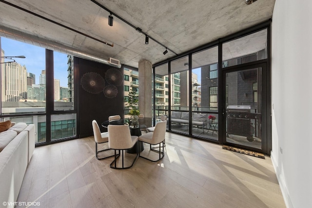 dining room with expansive windows, wood finished floors, a view of city, and rail lighting