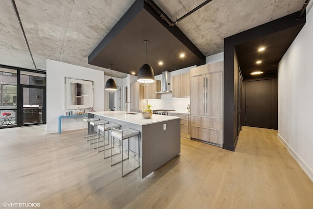 kitchen with paneled built in fridge, modern cabinets, light countertops, light wood-style floors, and light brown cabinets