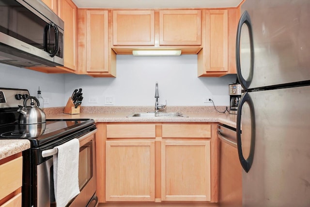 kitchen with appliances with stainless steel finishes, light countertops, light brown cabinets, and a sink