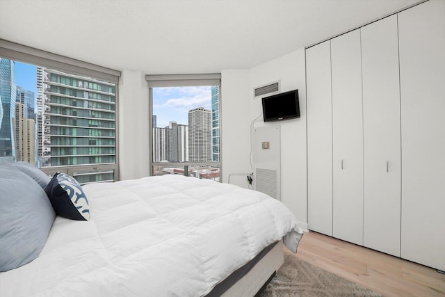 bedroom with light wood-type flooring, visible vents, and a textured ceiling