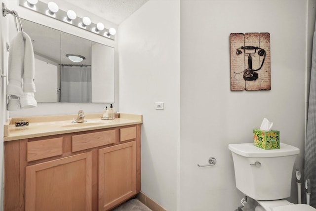 bathroom with a textured ceiling, vanity, toilet, and baseboards