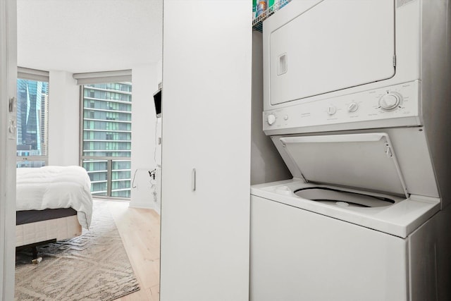 laundry room featuring light wood-style floors, laundry area, and stacked washer / dryer