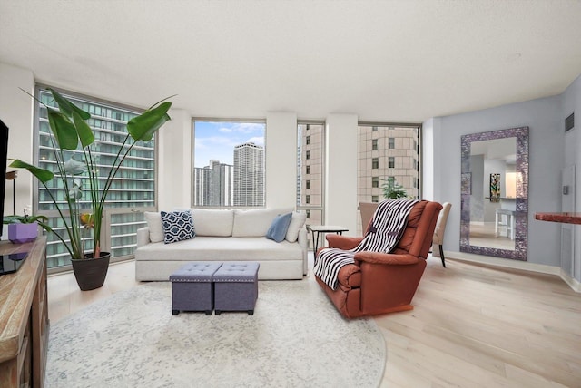 sitting room with a textured ceiling, wood finished floors, visible vents, and baseboards