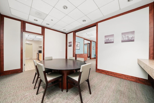 dining space with a paneled ceiling, light carpet, and baseboards