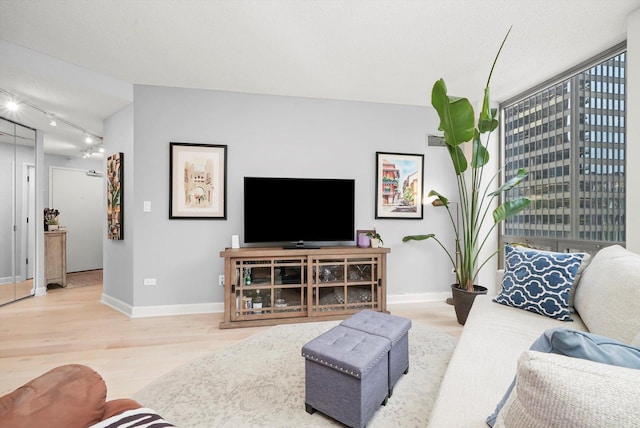 living room with visible vents, a textured ceiling, track lighting, wood finished floors, and baseboards