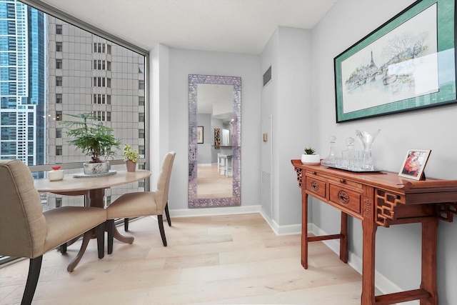 dining room with baseboards, visible vents, and light wood finished floors