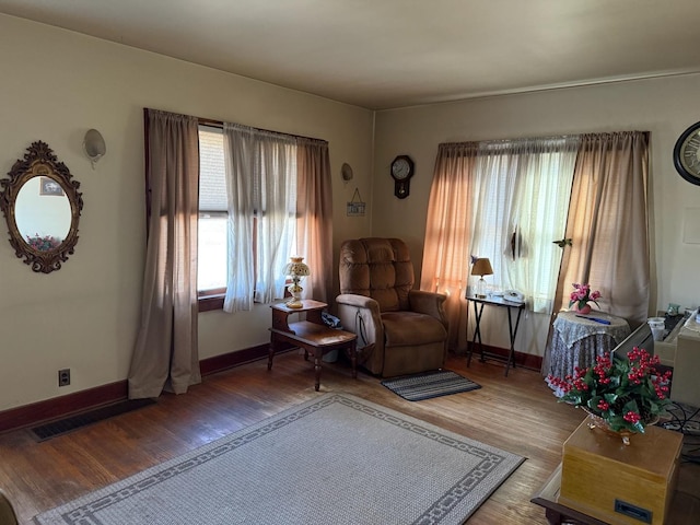 living area with wood finished floors, visible vents, and baseboards