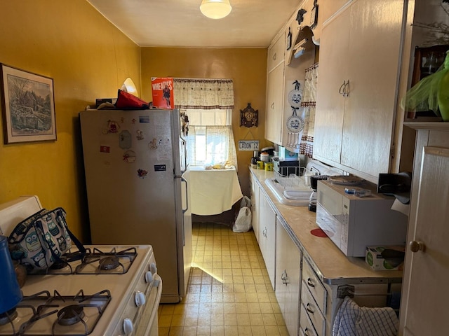 kitchen with white appliances, light countertops, a sink, and light floors