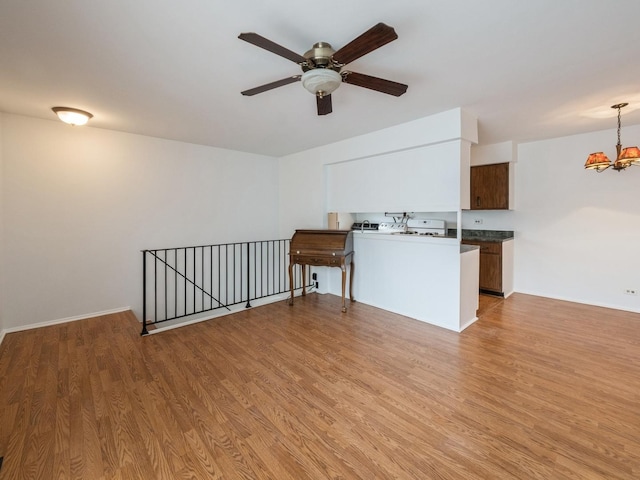 interior space with ceiling fan with notable chandelier, light wood-style flooring, and baseboards