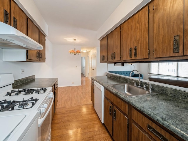 kitchen with white appliances, dark countertops, a sink, and under cabinet range hood