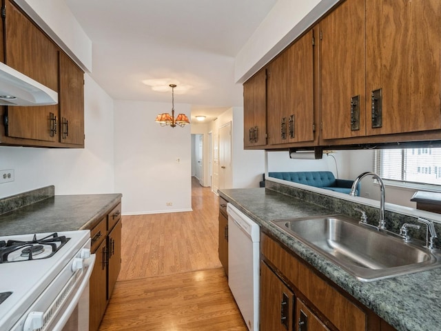 kitchen featuring a chandelier, white appliances, a sink, light wood-type flooring, and dark countertops