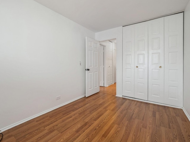 unfurnished bedroom with a closet, wood finished floors, and baseboards