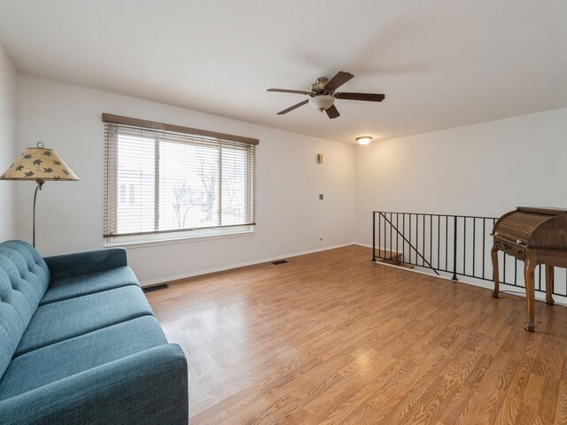 living area with light wood finished floors, baseboards, visible vents, and ceiling fan