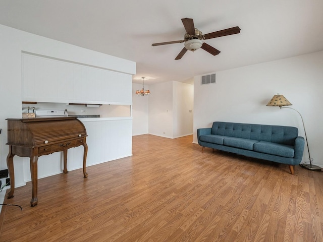 sitting room with ceiling fan with notable chandelier, light wood-type flooring, and visible vents