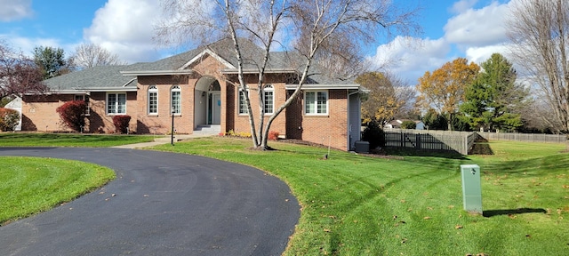 view of front of house featuring brick siding, fence, and a front yard