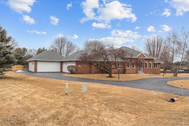 ranch-style home with a garage, brick siding, driveway, and a front lawn