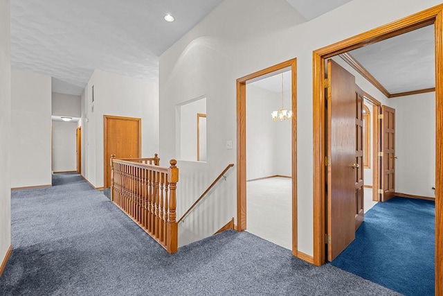 hallway featuring carpet, baseboards, and an upstairs landing