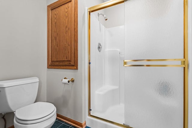 bathroom featuring baseboards, a shower stall, toilet, and tile patterned floors