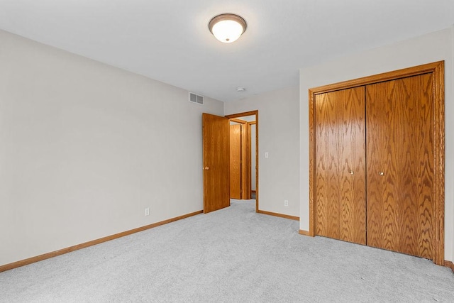 unfurnished bedroom with carpet floors, a closet, visible vents, and baseboards