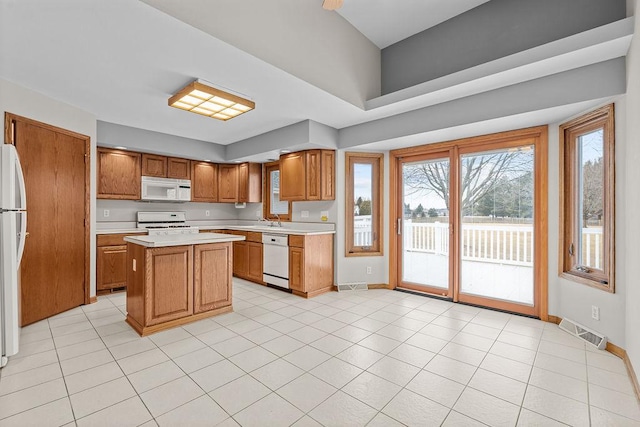 kitchen with brown cabinets, white appliances, light countertops, and visible vents