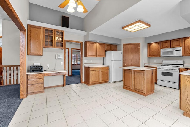 kitchen with white appliances, a kitchen island, glass insert cabinets, brown cabinets, and light countertops