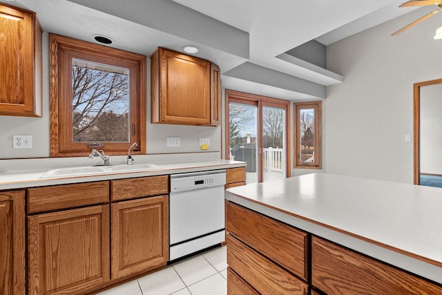 kitchen featuring light countertops, white dishwasher, a sink, and brown cabinets