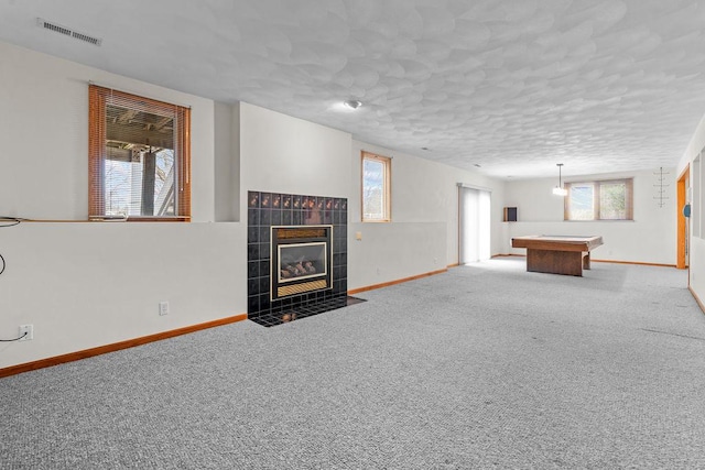 unfurnished living room with baseboards, a fireplace, visible vents, and a textured ceiling