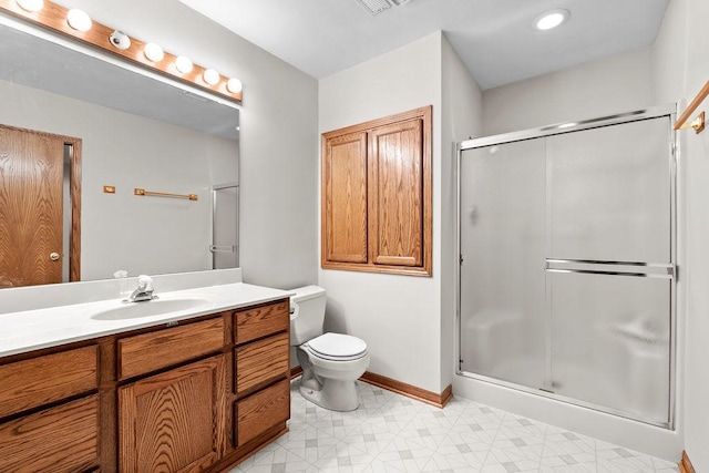 bathroom with toilet, vanity, a shower stall, baseboards, and tile patterned floors