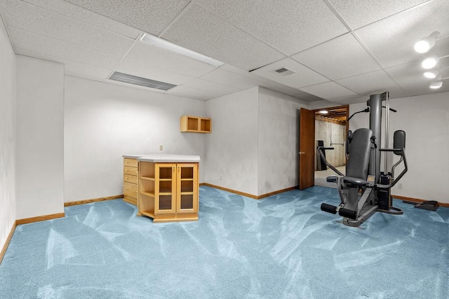 workout room with a paneled ceiling and baseboards