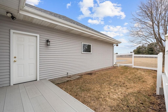 view of home's exterior with a shingled roof and fence