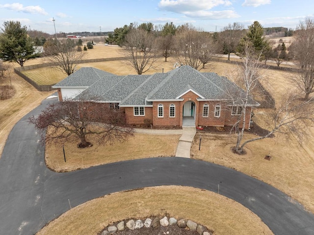 view of front of home featuring aphalt driveway, a shingled roof, and brick siding