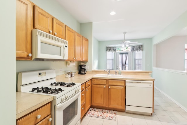 kitchen featuring light tile patterned floors, a peninsula, white appliances, a sink, and light countertops