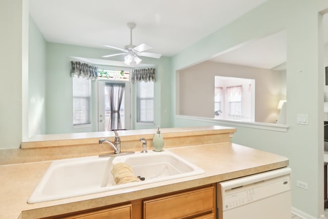 kitchen featuring light countertops, white dishwasher, a sink, and ceiling fan