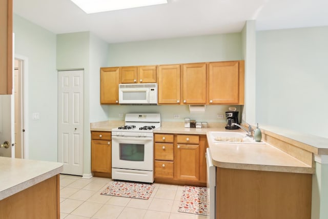 kitchen featuring light tile patterned floors, a peninsula, white appliances, a sink, and light countertops