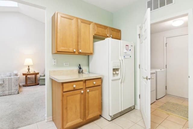 kitchen with light tile patterned flooring, visible vents, washer and dryer, light countertops, and white fridge with ice dispenser