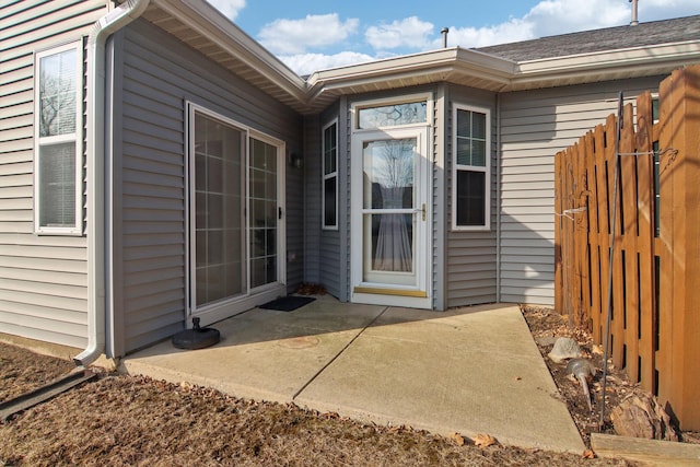 view of exterior entry featuring a patio and fence