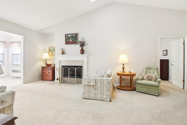 living room featuring carpet, baseboards, vaulted ceiling, and a tiled fireplace