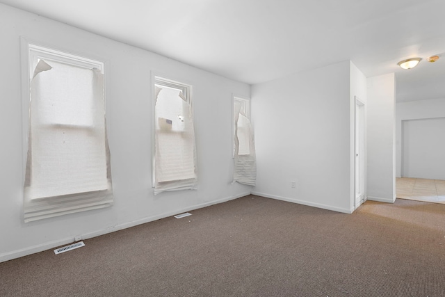 carpeted spare room featuring baseboards and visible vents