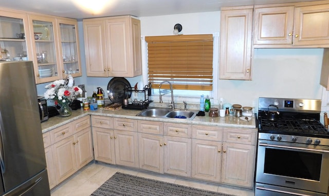 kitchen featuring stainless steel appliances, glass insert cabinets, a sink, and light tile patterned floors