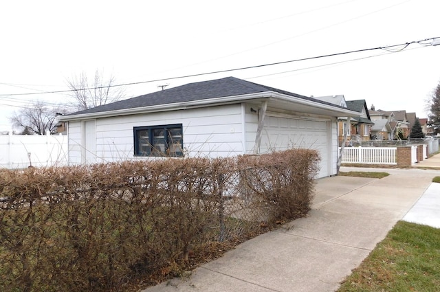 view of side of property featuring driveway, roof with shingles, and fence