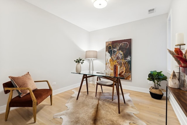 office space with light wood finished floors, visible vents, and baseboards