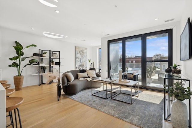 living room featuring light wood-type flooring, visible vents, and recessed lighting