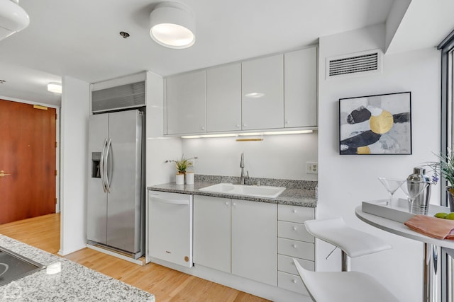 kitchen with a sink, visible vents, stainless steel fridge with ice dispenser, dishwasher, and light wood finished floors