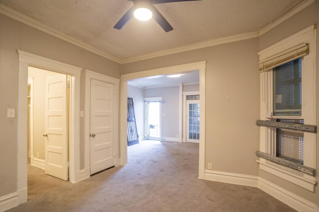 interior space with carpet floors, baseboards, ornamental molding, and ceiling fan