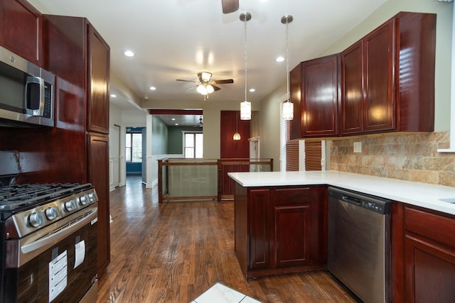 kitchen with a peninsula, dark brown cabinets, appliances with stainless steel finishes, light countertops, and dark wood finished floors