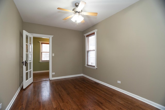 spare room with dark wood-type flooring, baseboards, and a ceiling fan