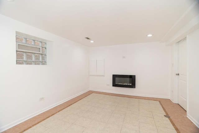 unfurnished living room featuring baseboards, light tile patterned floors, a glass covered fireplace, and recessed lighting