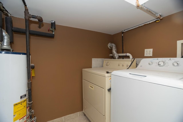 clothes washing area with light tile patterned floors, gas water heater, and washing machine and dryer