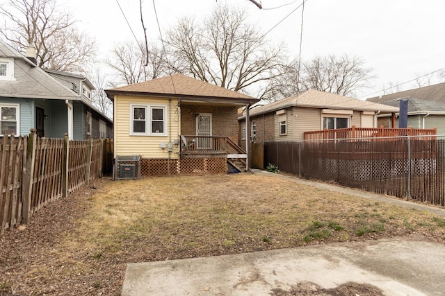 rear view of house featuring a fenced backyard and roof with shingles